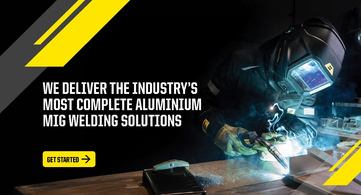 A skilled welder performing aluminum welding with a bright arc in a fabrication shop.